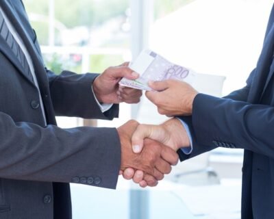 freepicdownloader.com-businessmen-shaking-hands-exchanging-money-medium